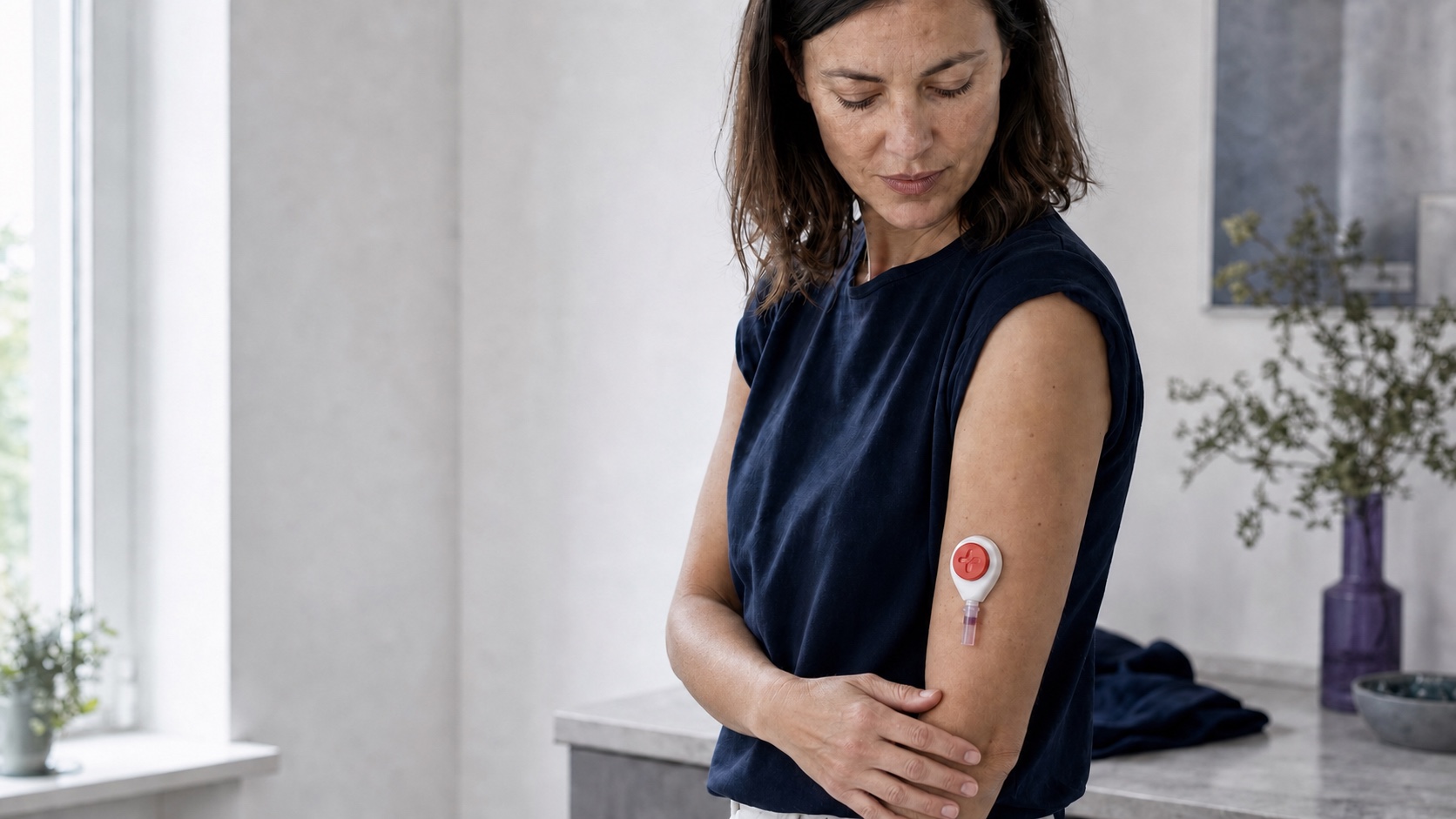 Frau mit anatomisch korrekt sitzendem Probenentnahmegerät am Oberarm in einer ruhigen häuslichen Umgebung